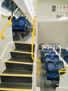 blue seats on a train with yellow railings and handrails next to each other