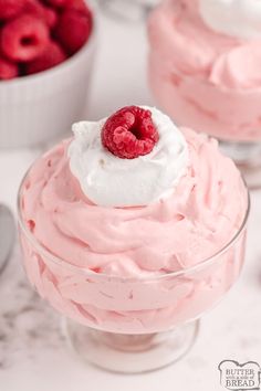 two desserts with raspberries and whipped cream in them on a white table