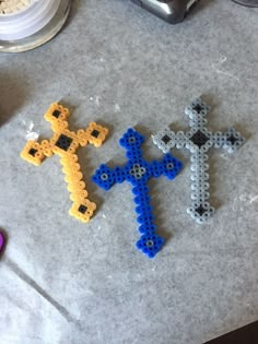 two cross shaped beads sitting on top of a table next to a pair of scissors