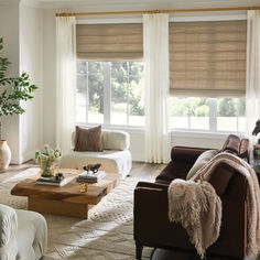 A clean, modern eclectic living room with mixed neutral shades on furniture and decor. A textured cream rug on the floor and natural woven wood roman shades on the windows, layered with off-white drapery. Framed Windows, Pleated Drapery, Spring Window, Wide Windows, Beautiful Windows, Design Gallery, Patio Doors