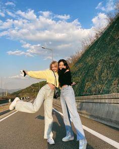 two young women posing for a photo on the street with their arms around each other