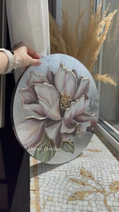 a person holding a plate with a flower painted on it