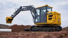 a yellow excavator is parked in the dirt