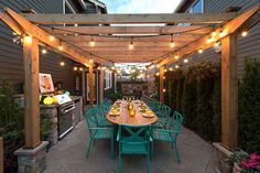 an outdoor dining area is lit up with string lights and green chairs around the table