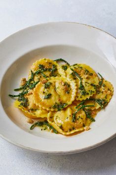 a white plate topped with ravioli and spinach