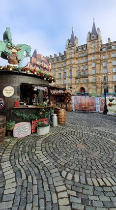 an outdoor market in the middle of a cobblestone street with buildings in the background