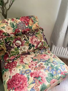 a bed with floral sheets and pillows on top of it next to a radiator