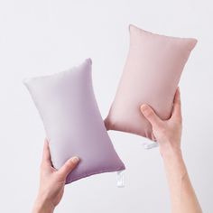 two pillows being held up in front of each other