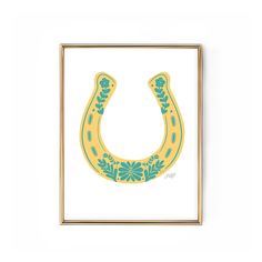 a yellow and blue horse shoe with flowers on it's side in a gold frame