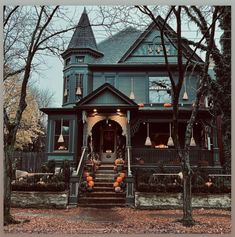 an old victorian style house with pumpkins on the front porch and steps leading up to it