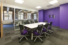 an empty conference room with purple walls and black chairs in front of a white table