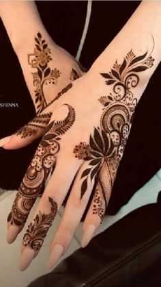 a woman's hand with henna tattoos on it, and her hands in the middle