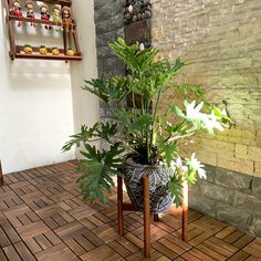 a potted plant sitting on top of a wooden stand next to a brick wall