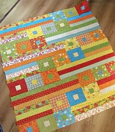 a person standing next to a colorful patchwork quilt on a wooden floor in front of a window