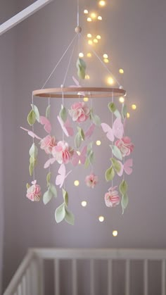 a baby crib with pink and green flowers hanging from it's ceiling fixture