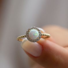 a close up of a person holding a ring with a white opal in it