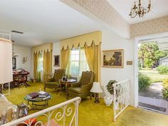 a living room filled with furniture next to a window covered in yellow drapes and curtains