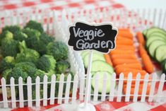 there is a sign that says veggie garden in front of some broccoli and carrots