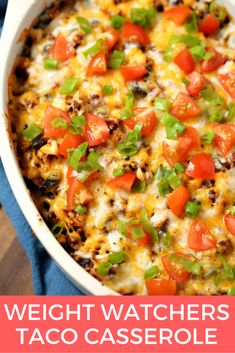 a casserole dish with tomatoes, green onions and cheese in it on a blue towel