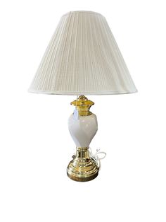 a lamp with a white shade on it and a gold trimming around the base