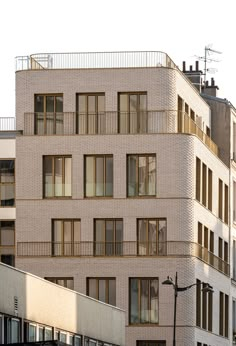 an apartment building with balconies and windows on the top floor, next to a street light