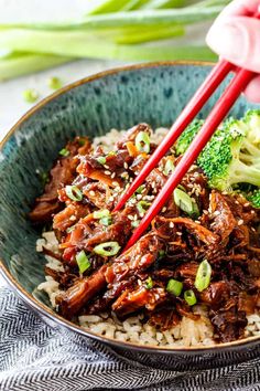 a bowl filled with beef, broccoli and rice topped with chopsticks