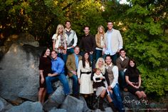 a large group of people posing for a photo in front of some rocks and trees