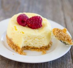 a piece of cheesecake with raspberries on top and a fork in it