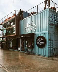 a man standing on top of a blue shipping container next to a tall building with a bicycle sign