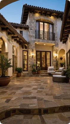 an outdoor patio with stone steps and potted plants in front of a house at dusk