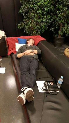 a man laying on top of a black couch