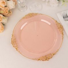 a pink and gold plate sitting on top of a table next to some white flowers