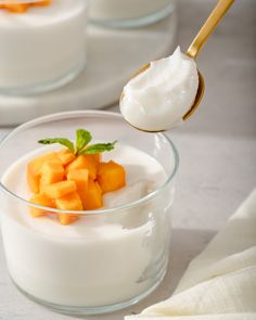 a spoonful of yogurt and fruit in a glass bowl