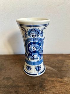 a blue and white vase sitting on top of a wooden table next to a wall