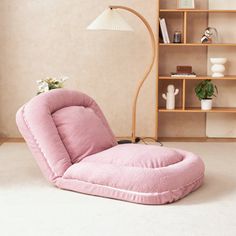 a pink bean bag chair sitting in front of a book shelf