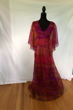 I am offering a lovely Sherman of London 1970s dress. This amazing floor length dress offers so many great features starting with the colors magenta and orange. It has semi sheer elbow length petal sleeves. The neckline is a v meeting the fitted midriff. The skirt is flared. The body of the dress is lined. This is an iconic 1970s dress.  Measurements on request.It is marked as a size 12, however in contemporary sizing, it seems a small. 1970s Dresses Formal, 70s Summer Dress, 70s Prom Dress 1970s, Dresses From The 70s, 70s Dresses Formal, 1970 Clothes, Prom Dresses 70s, 70s Gown, 70s Outfits Women