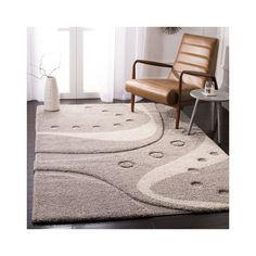 a living room area with a chair, rug and table in front of a window