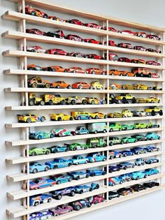 a wooden shelf filled with lots of toy cars on top of it's sides