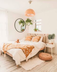 a bedroom with white walls and wooden flooring is decorated in neutral colors, including an orange bed spread