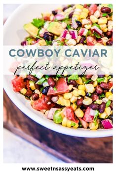 a white bowl filled with corn, avocado and black bean salad on top of a wooden cutting board