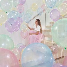 a woman sitting on the stairs surrounded by balloons