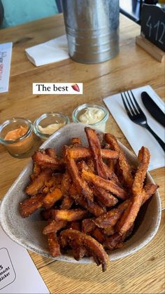 a bowl filled with fried food on top of a wooden table next to utensils