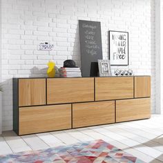 a white brick wall and wooden furniture in a room with an area rug on the floor