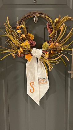 a wreath is hanging on the front door with an orange and white monogrammed tie