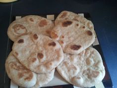 four pita breads sitting on top of a black and white tray with holes