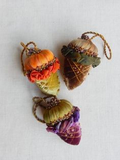 three small pumpkins are sitting next to each other on a white tablecloth surface