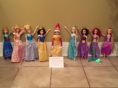 a group of dolls standing next to each other in front of a wall with a sign on it