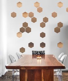 a wooden table sitting in front of a white wall with gold hexagons on it