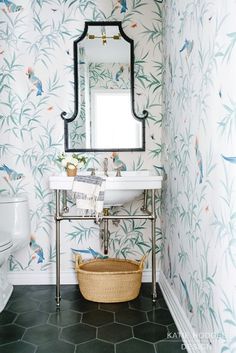 a bathroom with floral wallpaper and a mirror above the sink, along with a wicker basket on the floor