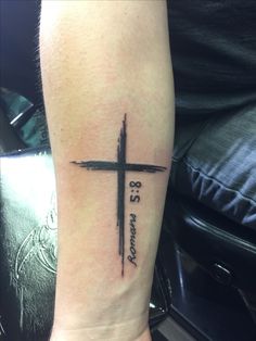 a cross tattoo on the arm with words written across it and an arrow in the middle